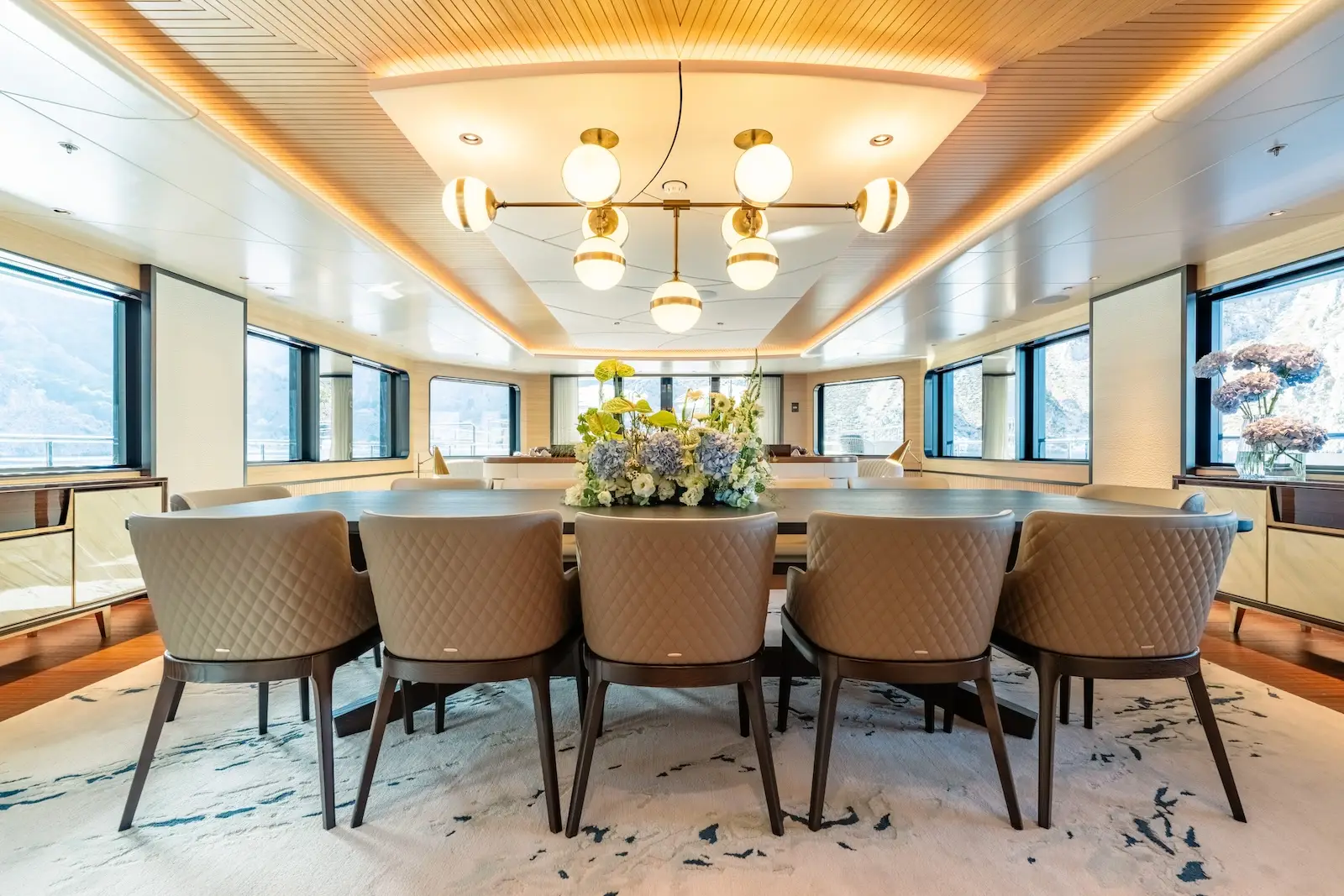 Dining composition with a long table set against full-height glazing
