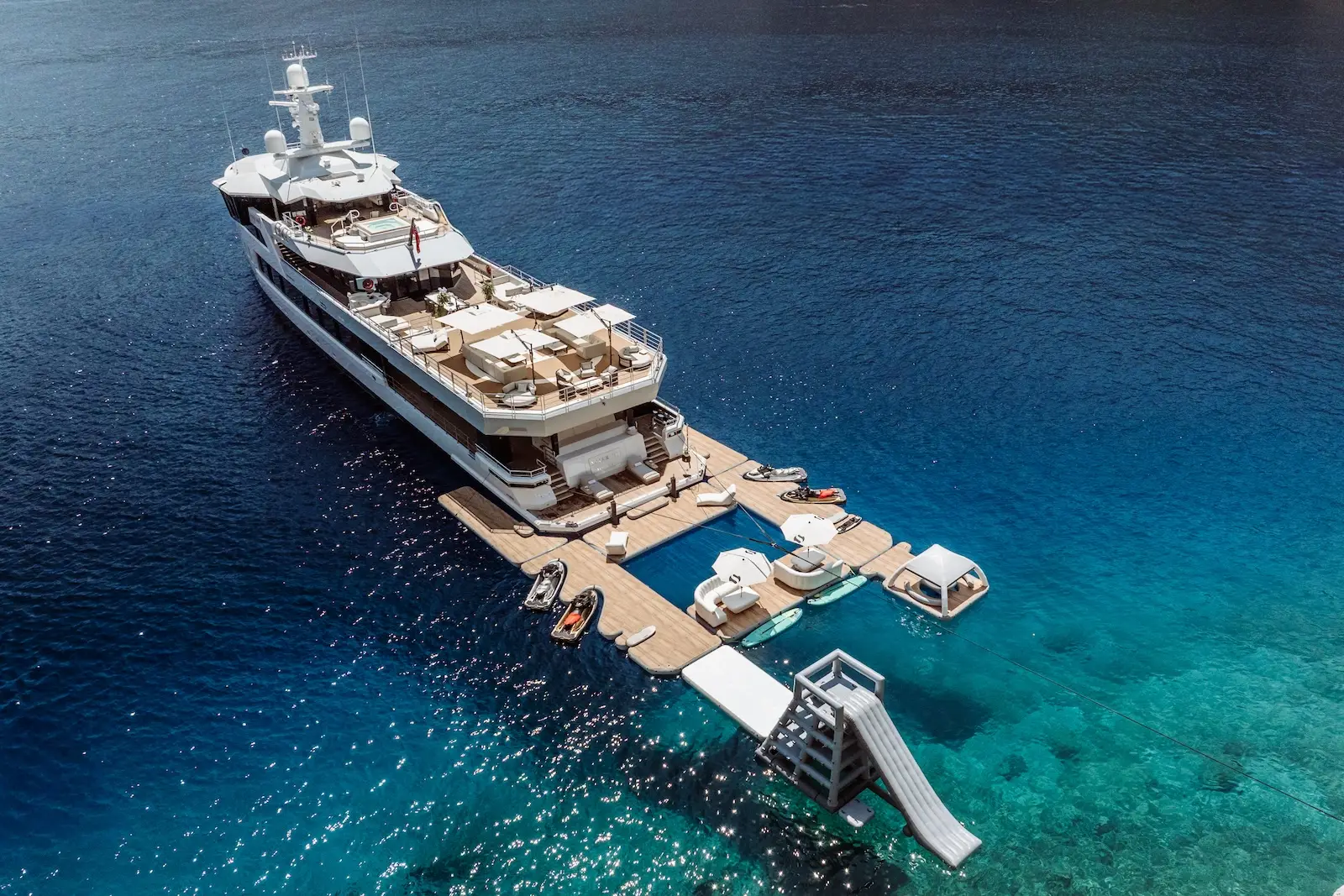 Aerial of AFTER YOU at anchor over turquoise water with her floating sea terrace, pool and toys deployed